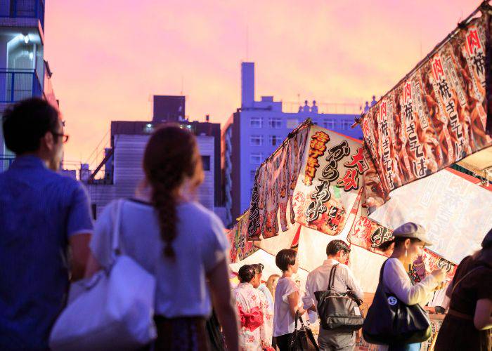 The sun setting in Osaka over busy yatai food stalls.